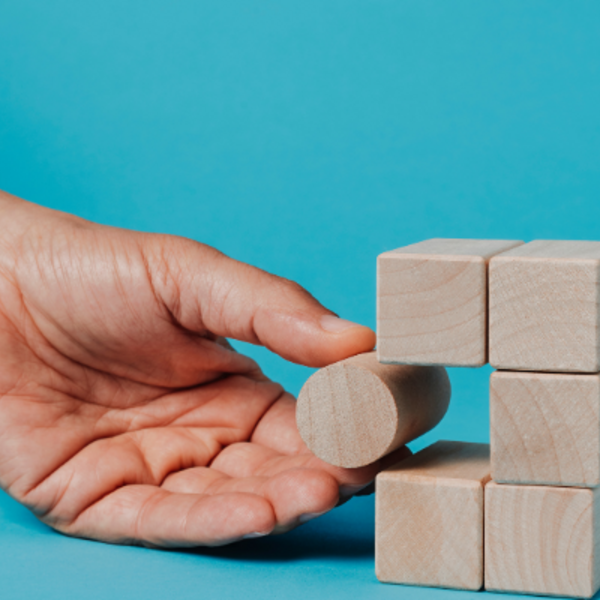 Titel: Strategische Problemlösung in der IT-Beratung

Beschreibung: Eine Hand platziert einen runden Holzblock in einen Würfel aus Holzklötzen, der vor einem hellblauen Hintergrund steht. Dieses Bild symbolisiert innovative Problemlösungen in einer IT-Age