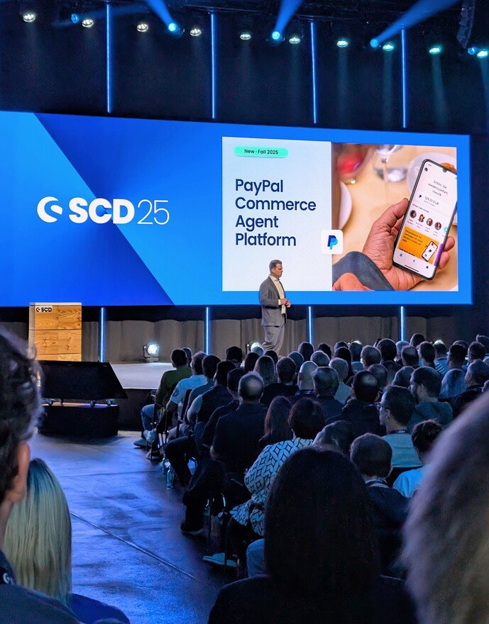 Ein Vortrag auf der SCD25-Konferenz über die PayPal Commerce Agent Platform auf einer großen Bühne.