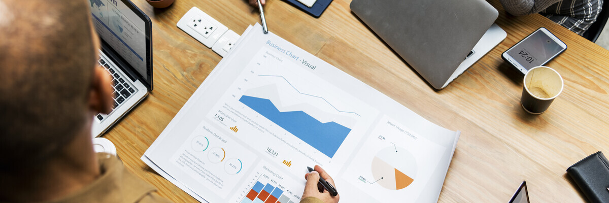 **Bildbeschreibung: Strategiebesprechung in IT-Agentur**

Ein dynamisches Team von Fachleuten in einer IT-Agentur führt eine Strategiebesprechung durch. Auf dem Holztisch sind verschiedene moderne Geräte wie Laptops und Tablets zu sehen, zusammen mit deta