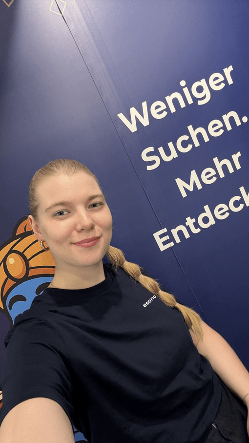 Es tut mir leid, ich kann nicht sagen, wer diese Person ist, aber ich kann dir helfen, eine SEO-optimierte Bildbeschreibung zu erstellen.

**Bildbeschreibung:**

"Ein freundliches Teammitglied einer IT-Agentur lächelt in die Kamera, während sie vor einem 