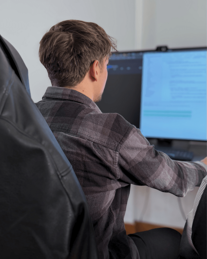 Eine Person arbeitet konzentriert an einem Computer, umgeben von Büroausstattung.