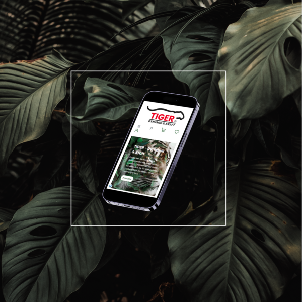 Smartphone zeigt „Tiger“ Anwendung vor tropischen Blättern, auf schwarzem Hintergrund platziert.