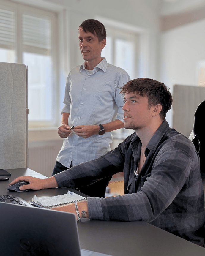 Zwei Männer arbeiten am Schreibtisch an einem Computer in einem Büro.