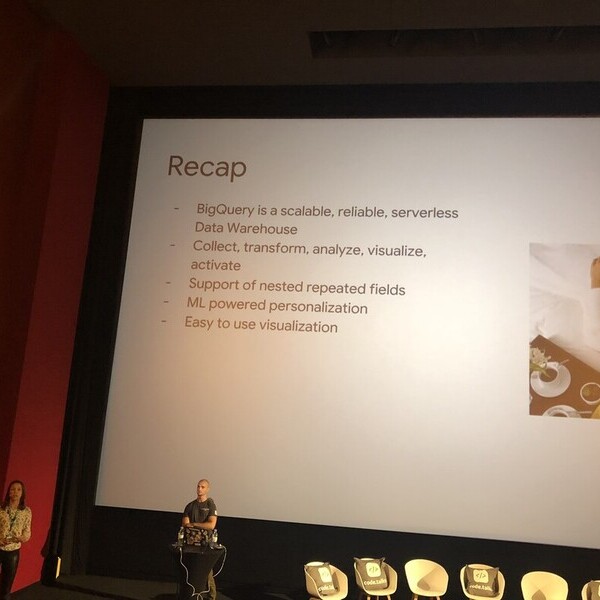 Präsentation zu BigQuery-Funktionen mit Moderatoren auf einer Bühne vor großen Bildschirmen.