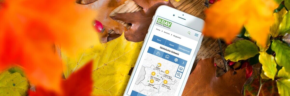Smartphone zeigt eine App zwischen Herbstblättern, mit geografischer Karte und Symbolen auf dem Display.