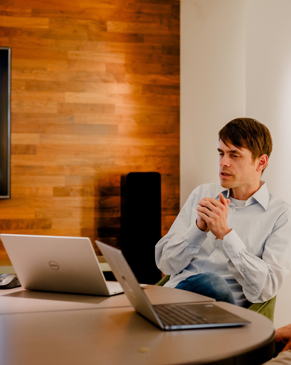 Eine Gruppe von Menschen in einem Meetingraum diskutiert vor einem Bildschirm mit Diagrammen und Laptops auf dem Tisch.