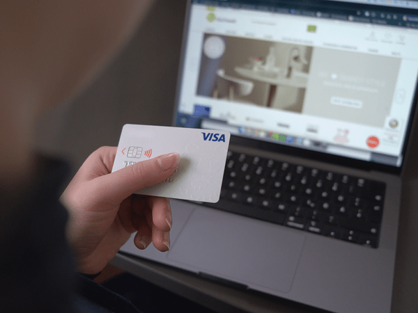 Nahaufnahme einer Person, die online mit einer Kreditkarte auf einem Laptop einkauft. Bildschirm zeigt eine Produktseite.