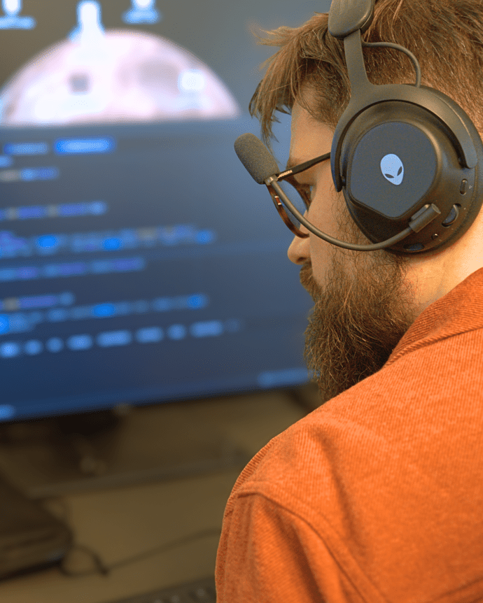 Ein Mann mit Headset arbeitet an einem Computerbildschirm mit komplexem Code.