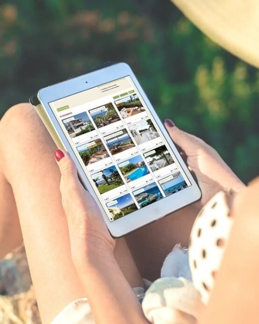 Person nutzt Tablet zur Ansicht von Immobilienbildern.