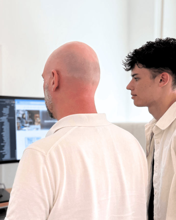 Zwei Personen betrachten Code auf einem Computerbildschirm in einem Büro.