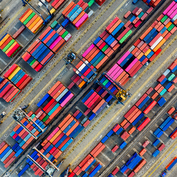 Luftaufnahme eines Containerterminals mit farbigen Containern, darauf verteilte Kräne für den Umschlag, symmetrisch angeordnet.