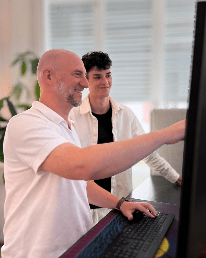 Zwei Personen betrachten einen Bildschirm im Büro, eine zeigt auf den Monitor.