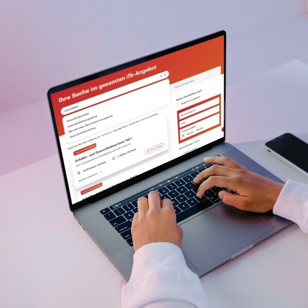 Person nutzt Laptop mit geöffneter Webseite zur Unternehmenssuche vor neutralem Hintergrund.