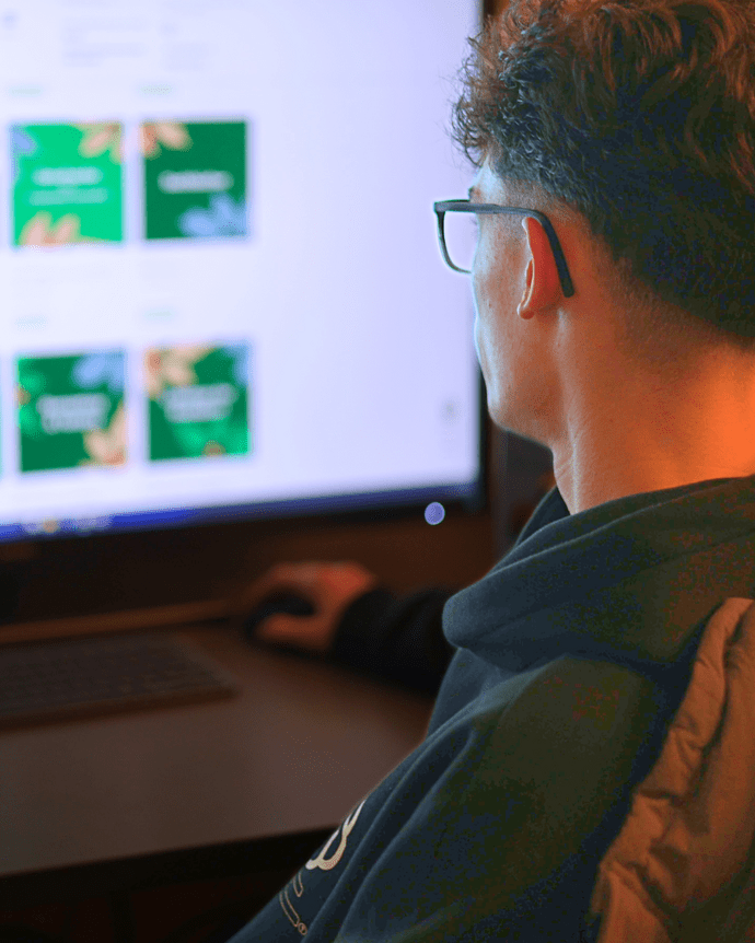 Person am Computer betrachtet bunte Bilder auf einem großen Monitor bei geringer Beleuchtung.