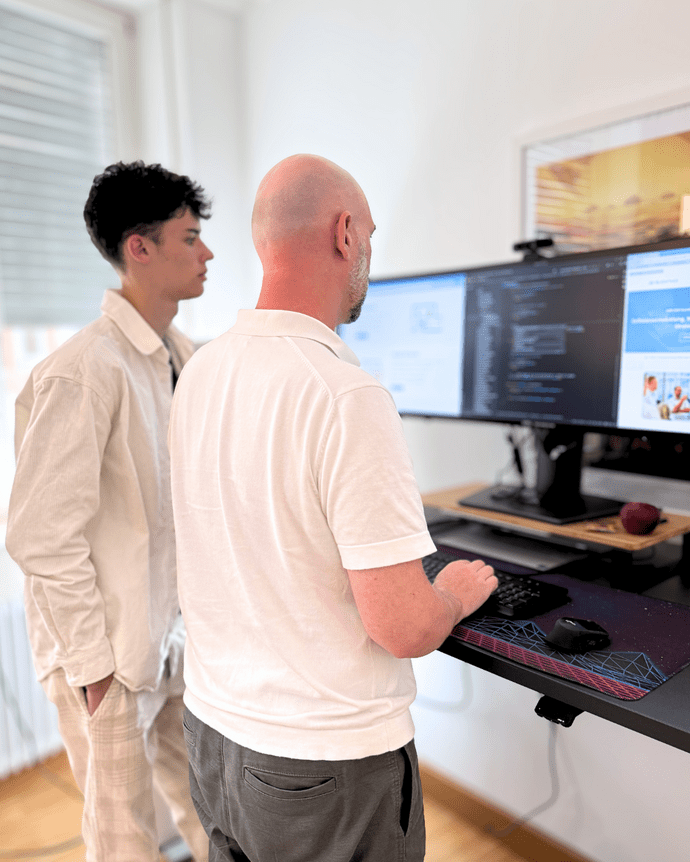 Zwei Personen arbeiten gemeinsam an einem Computerbildschirm im Büro.