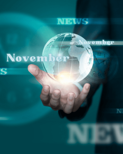 Hand hält schwebende Kugel mit "November"; umgeben von unscharfen Nachrichten-Schlagzeilen.
