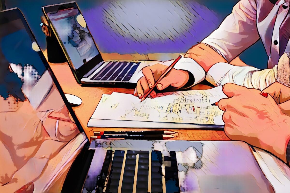 Person arbeitet an einem Schreibtisch mit Laptops und Papieren, macht Notizen mit Bleistiften in kreativer Umgebung.