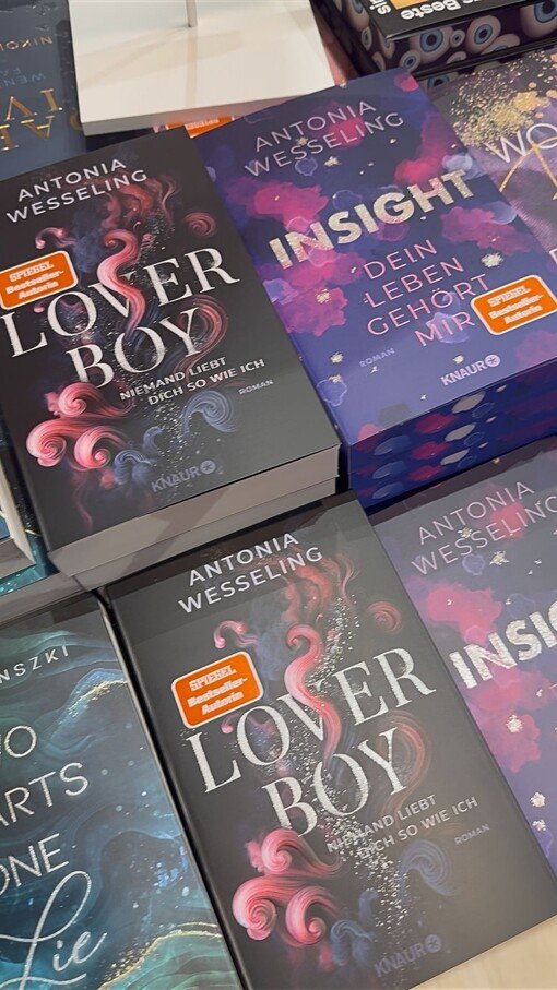 Bücherstapel von Antonia Wesseling, Titel „Loverboy“ und „Insight“. Cover in Blau- und Lila-Tönen mit abstrakten Mustern.